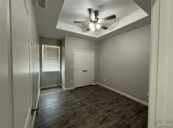 an empty room with wooden floor closet and chandelier fan