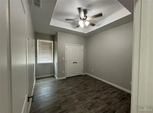 an empty room with wooden floor closet and chandelier fan