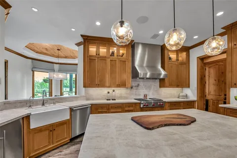 a kitchen with granite countertop a stove a sink a oven and a chandelier
