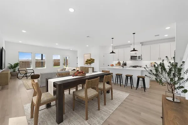 a room with stainless steel appliances lots of white furniture a dining table and chairs