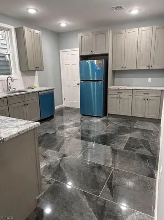 a kitchen with a sink a refrigerator and a stove top oven with white cabinets