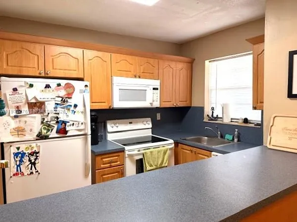 a kitchen with stainless steel appliances granite countertop a refrigerator a sink dishwasher and white cabinets with wooden floor