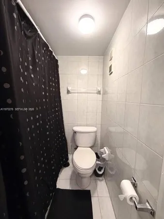 a bathroom with a toilet and a shower curtain