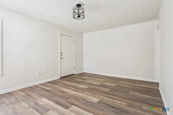 an empty room with windows and chandelier fan