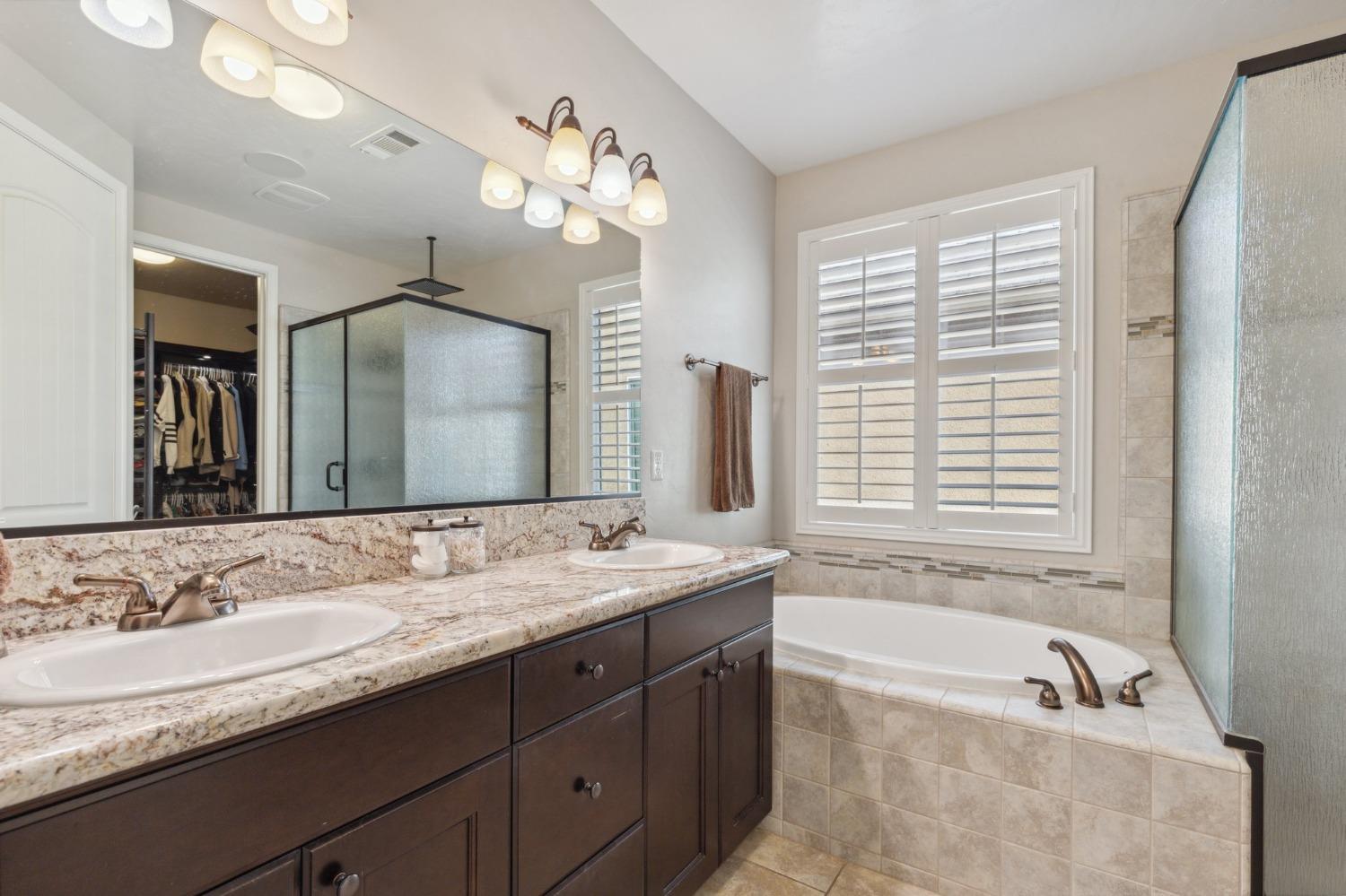 4217 Salem Lane Clovis, CA 93619 - Photo 21 of 57 a bathroom with a granite countertop tub a double vanity sink and a large mirror