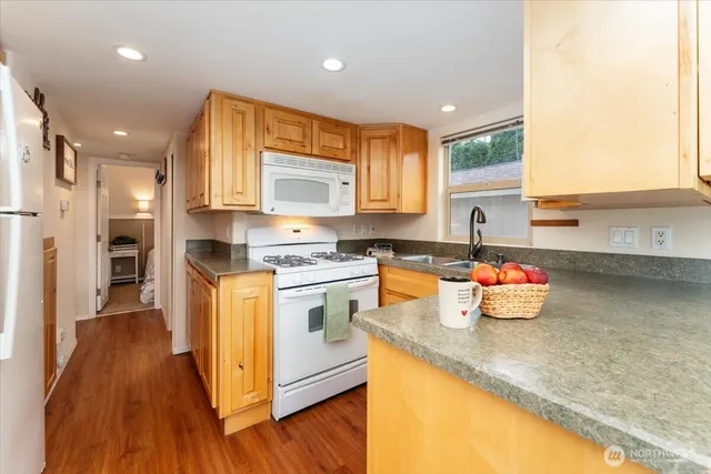 a kitchen with stainless steel appliances a stove a sink dishwasher and a refrigerator with wooden floor