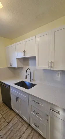 a kitchen with granite countertop white cabinets and sink