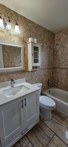 a bathroom with a granite countertop toilet a sink and a bathtub