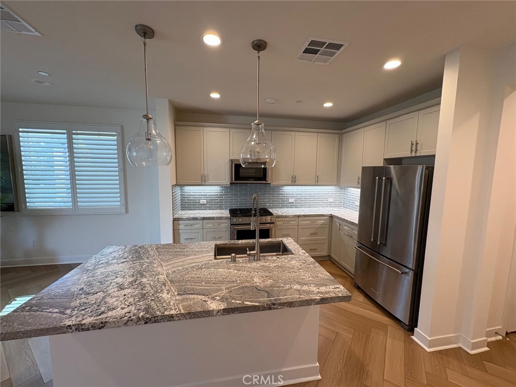 4252 East Sage Paseo, Unit 132 Ontario, CA 91761 - Photo 4 of 7 a kitchen with stainless steel appliances granite countertop refrigerator sink microwave and stove