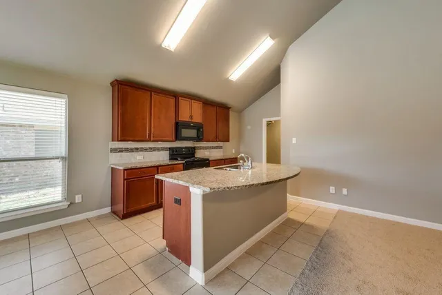 a kitchen with stainless steel appliances granite countertop a stove a sink and a microwave
