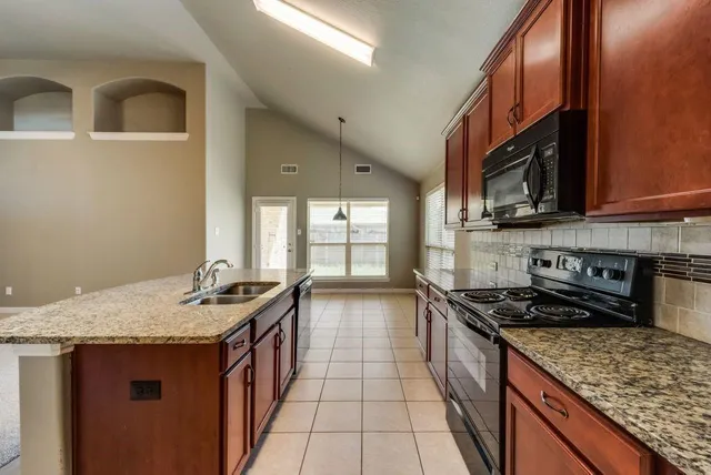 a kitchen with stainless steel appliances granite countertop a stove a sink and a microwave