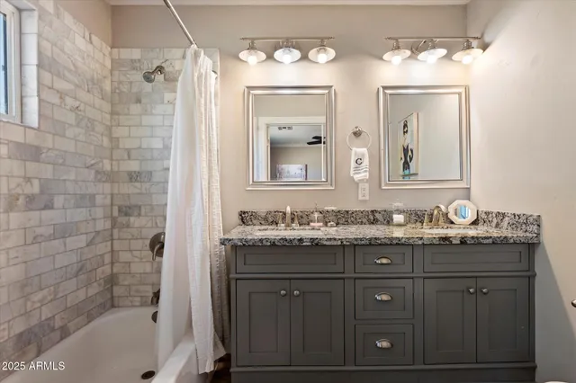 a bathroom with a granite countertop sink a mirror a vanity and a bathtub