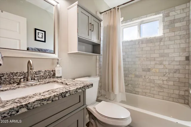 a bathroom with a granite countertop toilet sink and mirror
