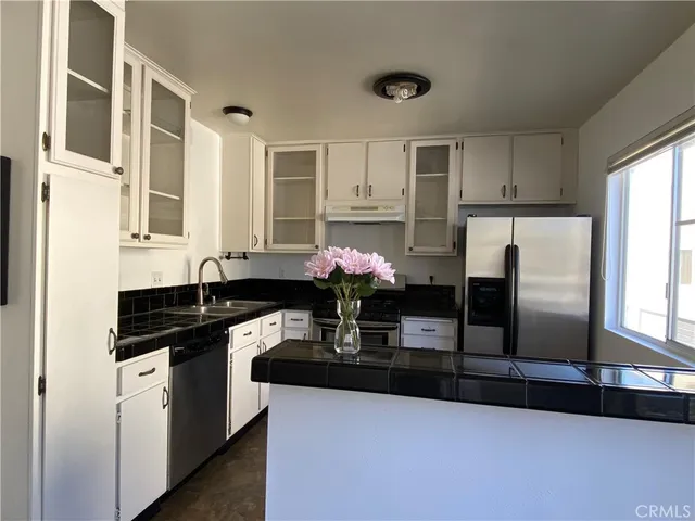 a kitchen with granite countertop a sink cabinets and stainless steel appliances