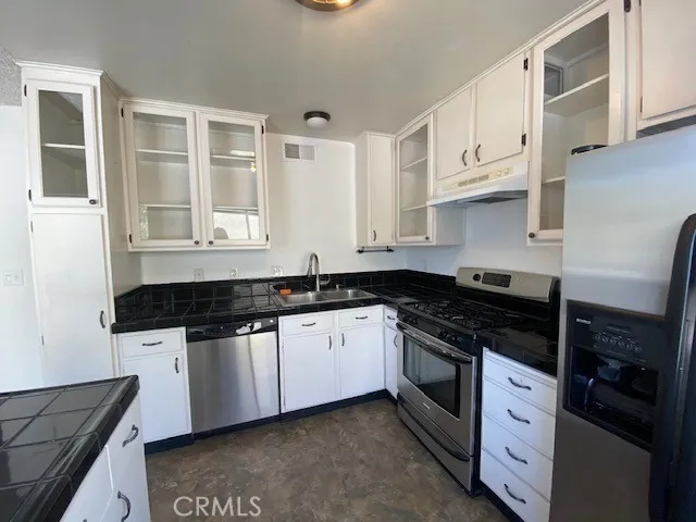 a kitchen with granite countertop white cabinets and stainless steel appliances