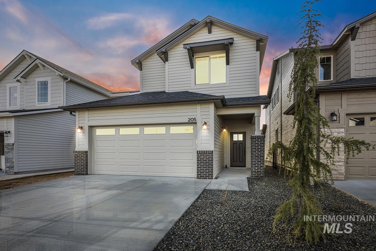 View of front of house with concrete driveway, roof with shingles, brick siding, and an attached garage