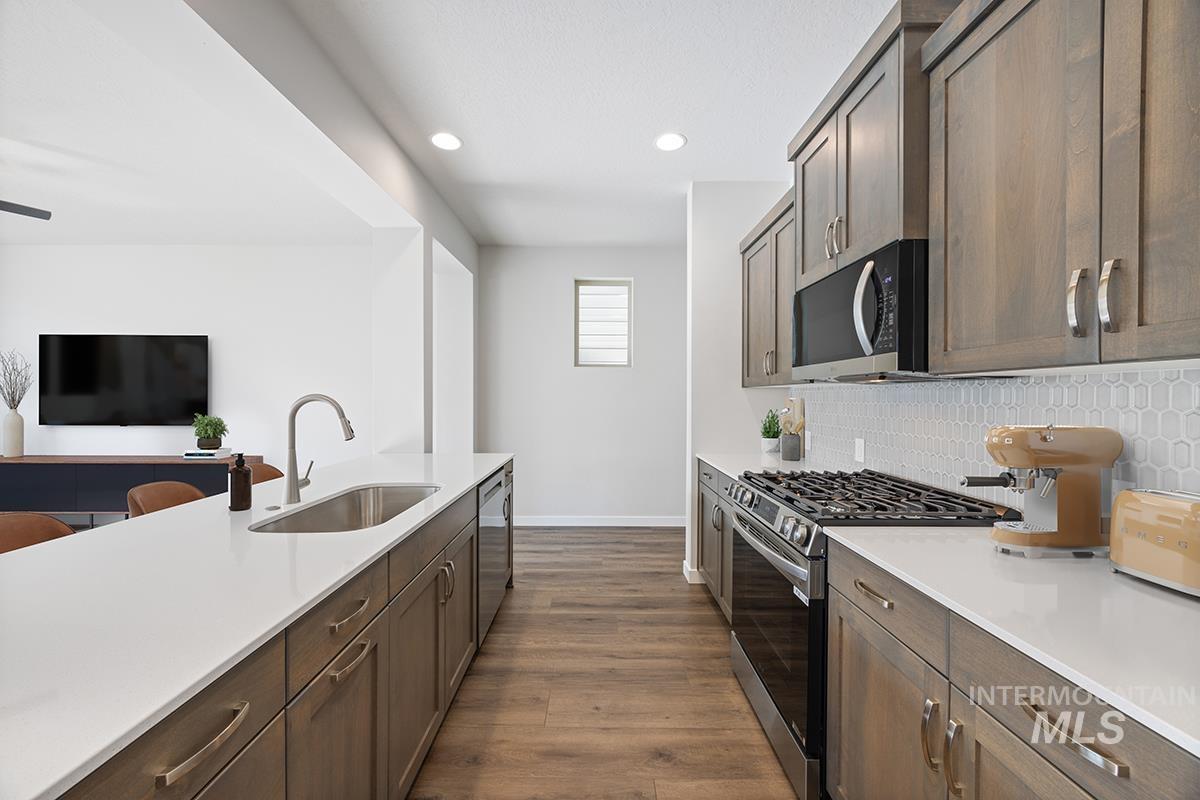 205 West Broyhill Street Meridian, ID 83642 - Photo 4 of 20 Kitchen featuring stainless steel appliances, dark wood-style floors, tasteful backsplash, recessed lighting, and dark wood finish cabinets