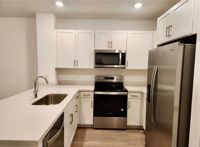 a kitchen with stainless steel appliances granite countertop a refrigerator a sink a stove a microwave and island