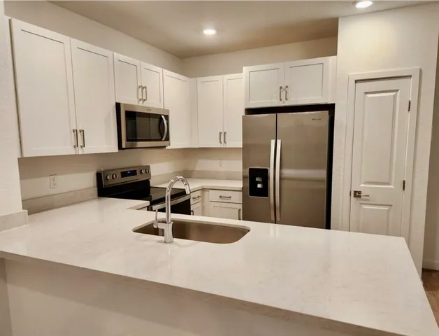 a kitchen with stainless steel appliances a refrigerator a sink a stove a microwave and cabinets