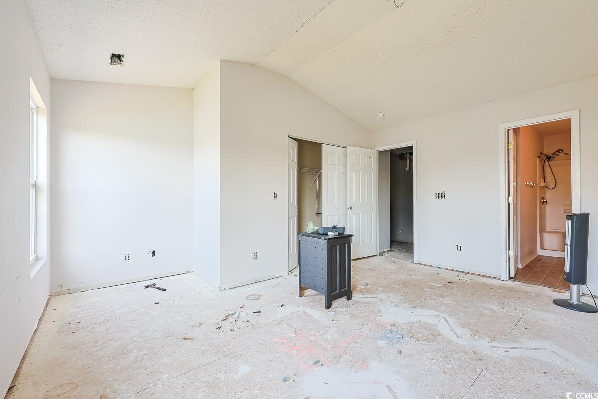 308 Kiskadee Loop, Unit E Conway, SC 29526 - Photo 12 of 28 Unfurnished bedroom with lofted ceiling, a closet, connected bathroom, and a textured ceiling
