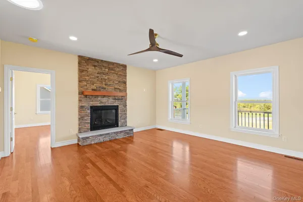 an empty room with wooden floor fireplace and windows