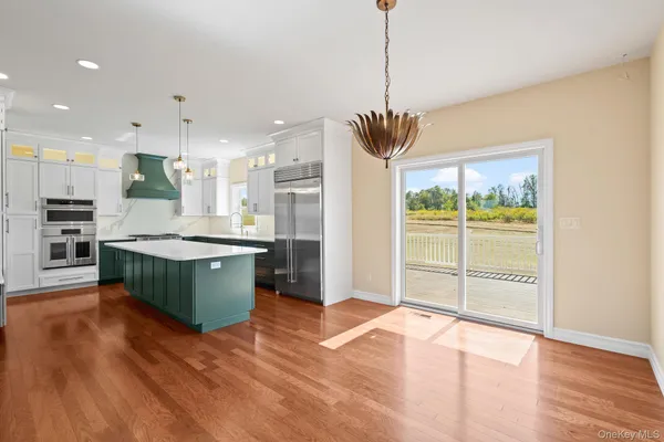a kitchen with stainless steel appliances granite countertop a refrigerator a oven a sink and a wooden floors