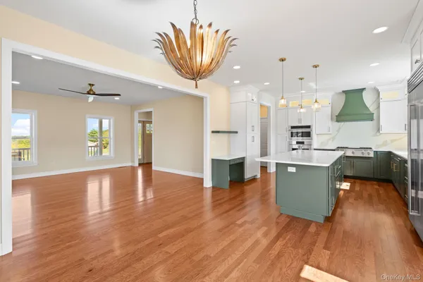 a view of a kitchen with kitchen island a sink wooden floor stainless steel appliances and a window