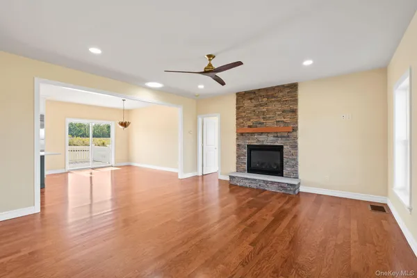 an empty room with wooden floor fireplace and windows