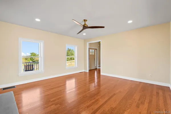 a view of an empty room with a window and wooden floor