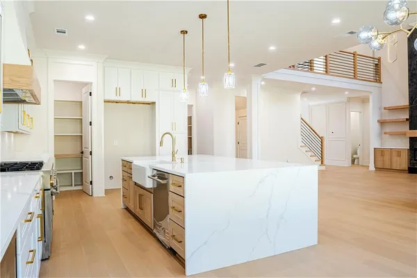 a large kitchen with stainless steel appliances kitchen island granite countertop a refrigerator a oven and a wooden floors