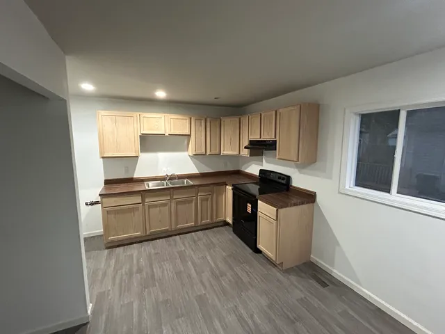 a kitchen with granite countertop a stove top oven sink and cabinets