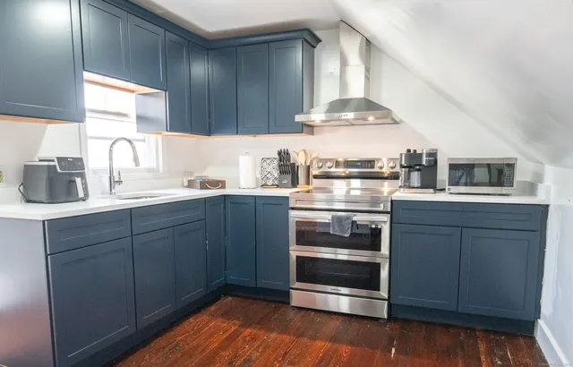 a kitchen with stainless steel appliances a stove and white cabinets