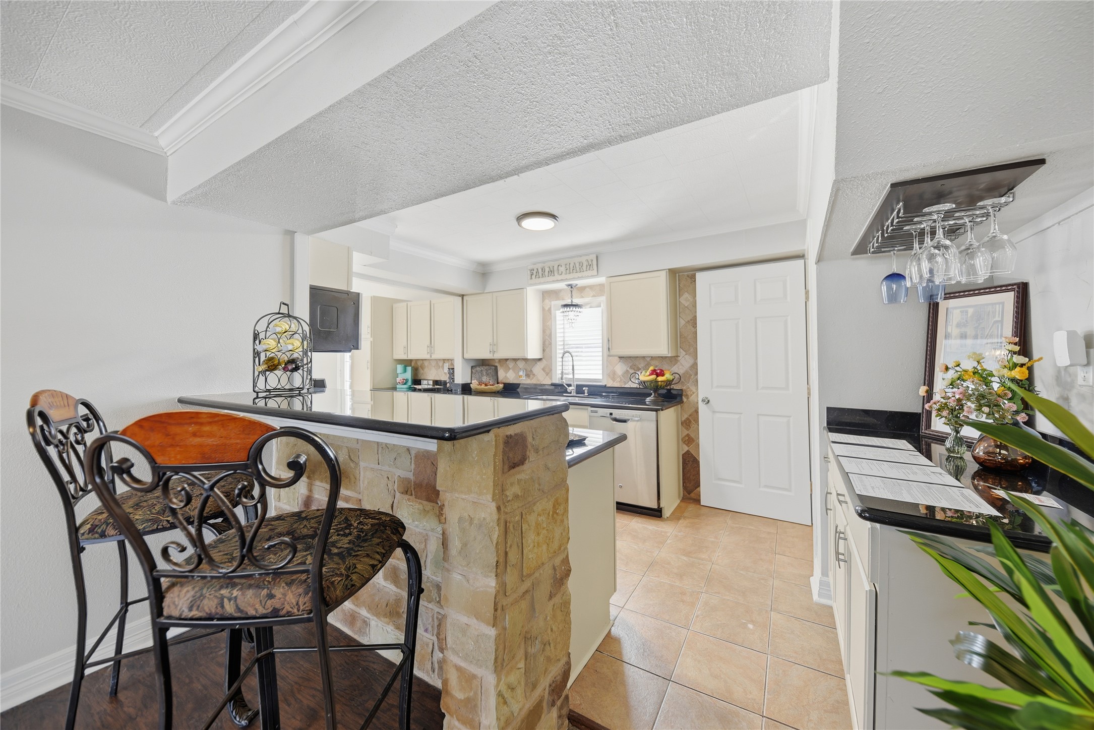 1702 Rampart Street Columbus, TX 78934 - Photo 23 of 38 Kitchen featuring crown molding, dark countertops, a textured ceiling, a breakfast bar, and a peninsula