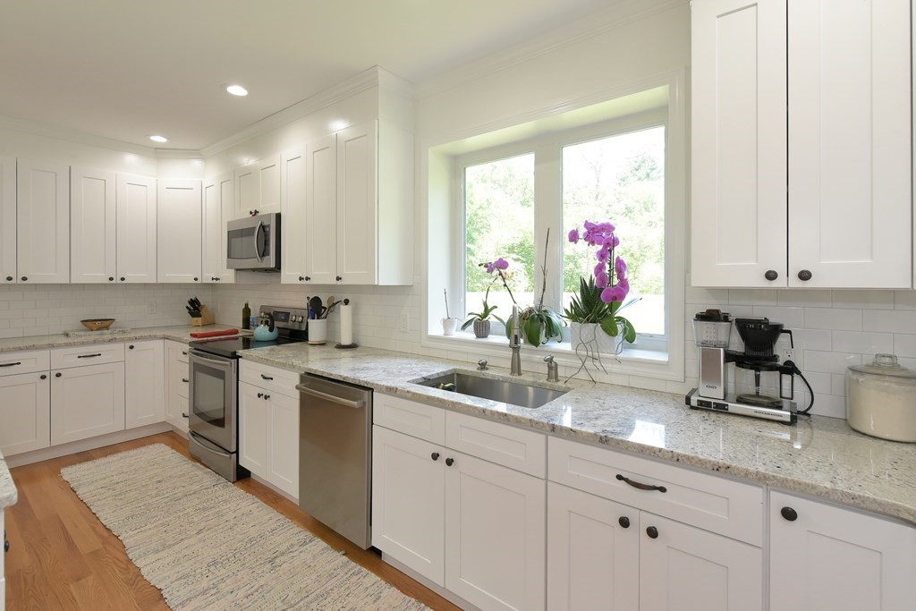 31 Elm Street Upton, MA 01568 - Photo 4 of 33 a kitchen with granite countertop a sink white cabinets and stainless steel appliances
