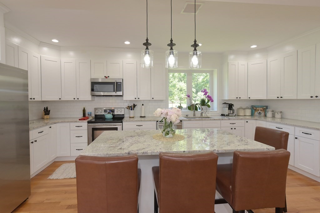 31 Elm Street Upton, MA 01568 - Photo 7 of 33 a kitchen with kitchen island granite countertop a table chairs microwave and cabinets