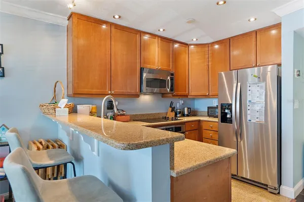 a kitchen with stainless steel appliances granite countertop a refrigerator a sink a stove a microwave and island