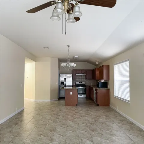 a kitchen with stainless steel appliances kitchen island granite countertop a refrigerator oven stove a sink dishwasher and white cabinets with wooden floor