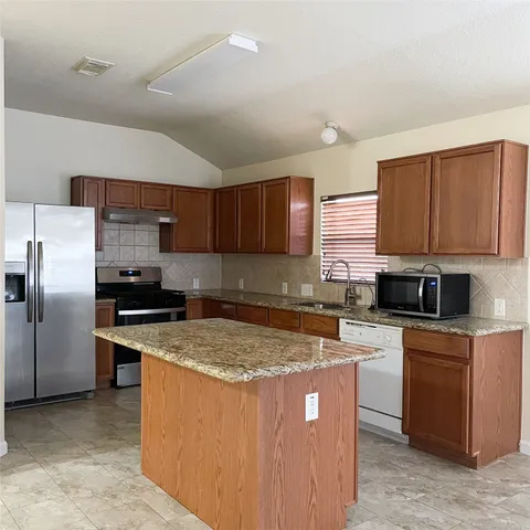 a kitchen with stainless steel appliances granite countertop a stove a sink dishwasher a refrigerator and a microwave oven