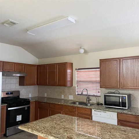 a kitchen with granite countertop wooden cabinets and stainless steel appliances