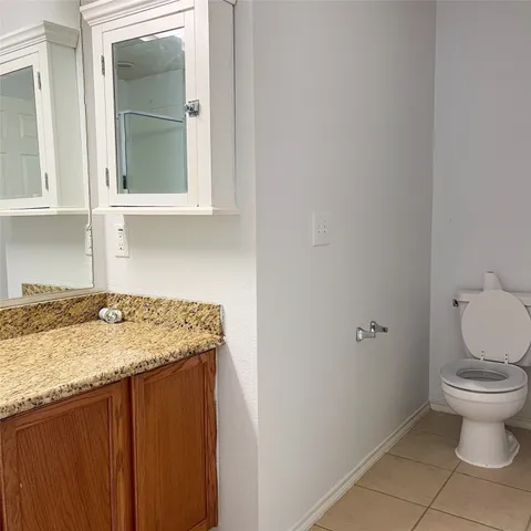 a bathroom with a granite countertop toilet and a sink