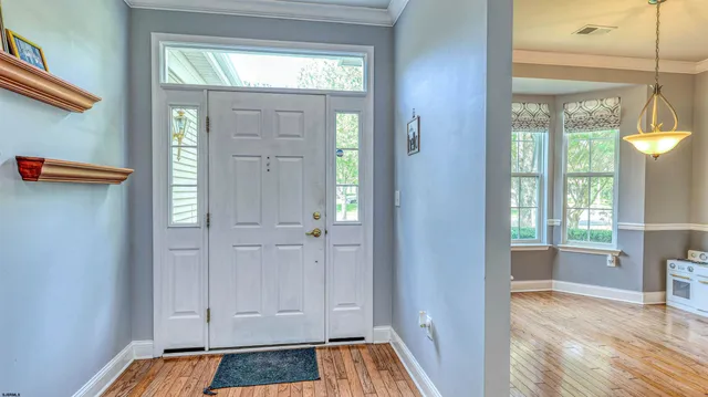 a view of front door with hallway and wooden floor