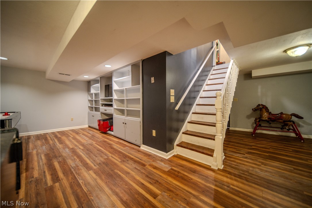 6549 Waterloo Road Atwater, OH 44201 - Photo 35 of 49 Lower level space featuring wood-finish flooring, built-in shelving, recessed lighting, and a painted staircase with white balusters