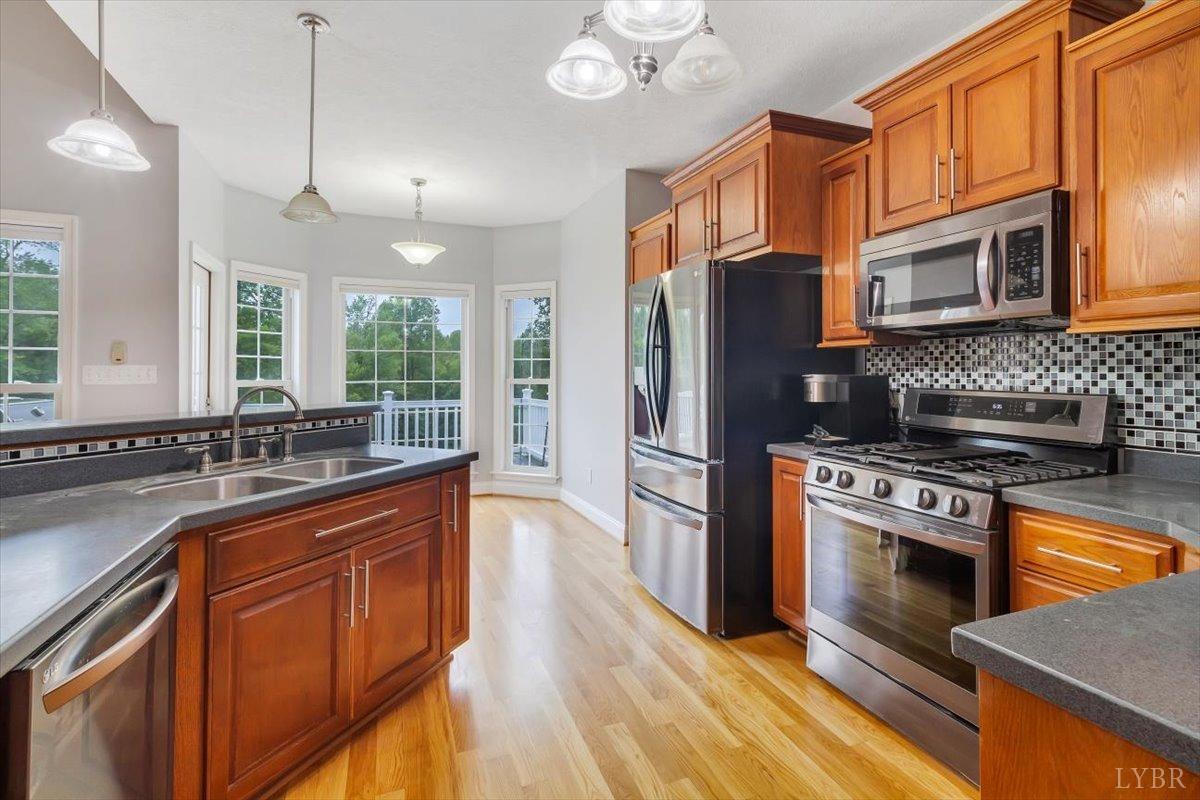 911 Police Tower Road Appomattox, VA 24522 - Photo 9 of 55 a kitchen with stainless steel appliances granite countertop a stove a sink dishwasher a refrigerator and a microwave oven with wooden floor