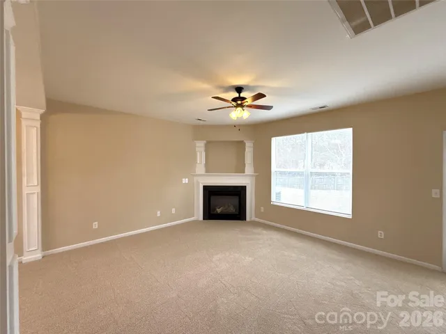 an empty room with windows and fireplace