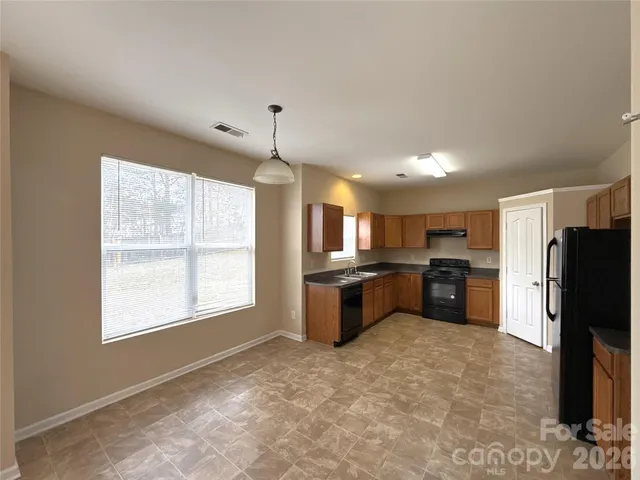 a large kitchen with stainless steel appliances kitchen island granite countertop a refrigerator and a stove top oven