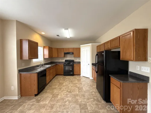 a kitchen with stainless steel appliances granite countertop a refrigerator a stove top oven and a sink