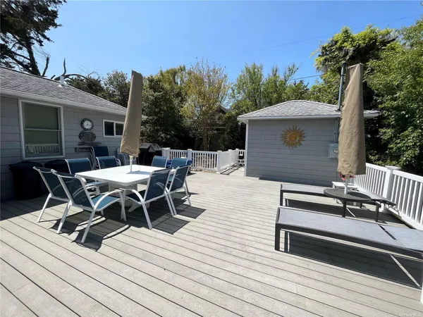 a view of a roof deck with table and chairs with wooden floor and fence