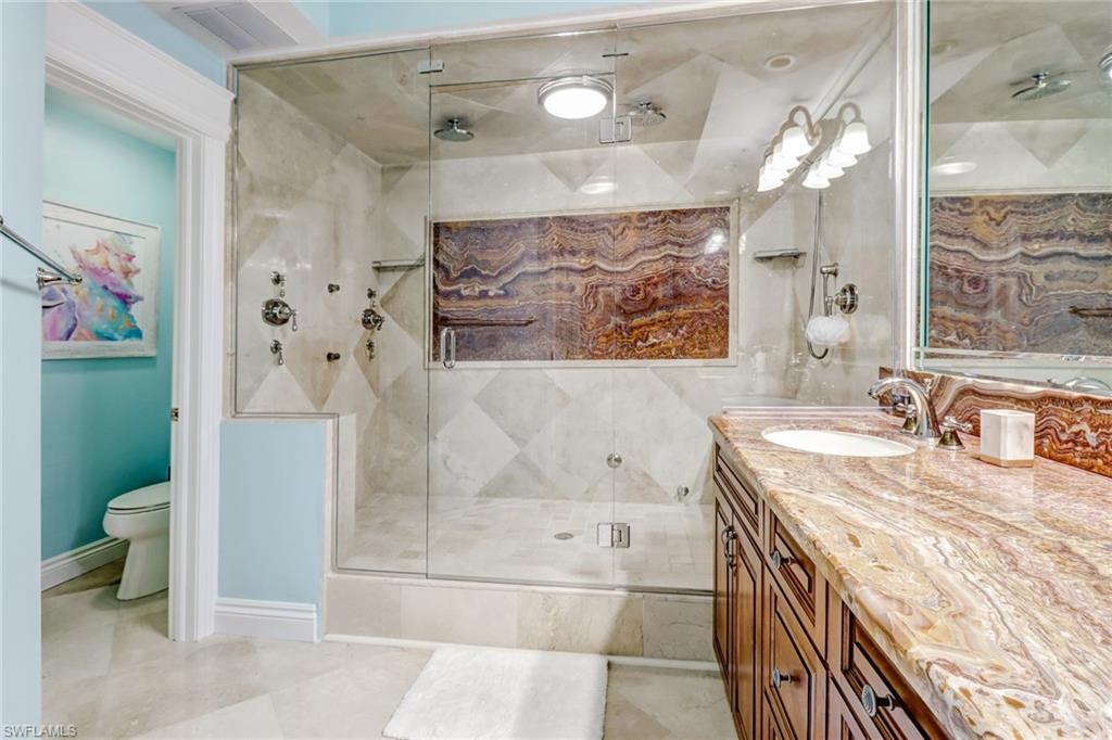 451 Bayfront Place, Unit 5307 Naples, FL 34102 - Photo 17 of 28 a bathroom with a granite countertop sink a toilet a mirror and shower