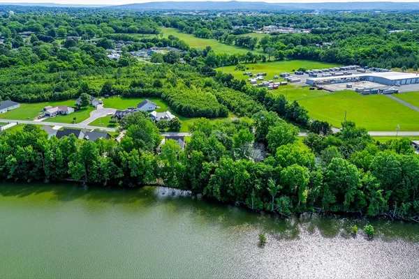 an aerial view of a residential houses with outdoor space and lake view
