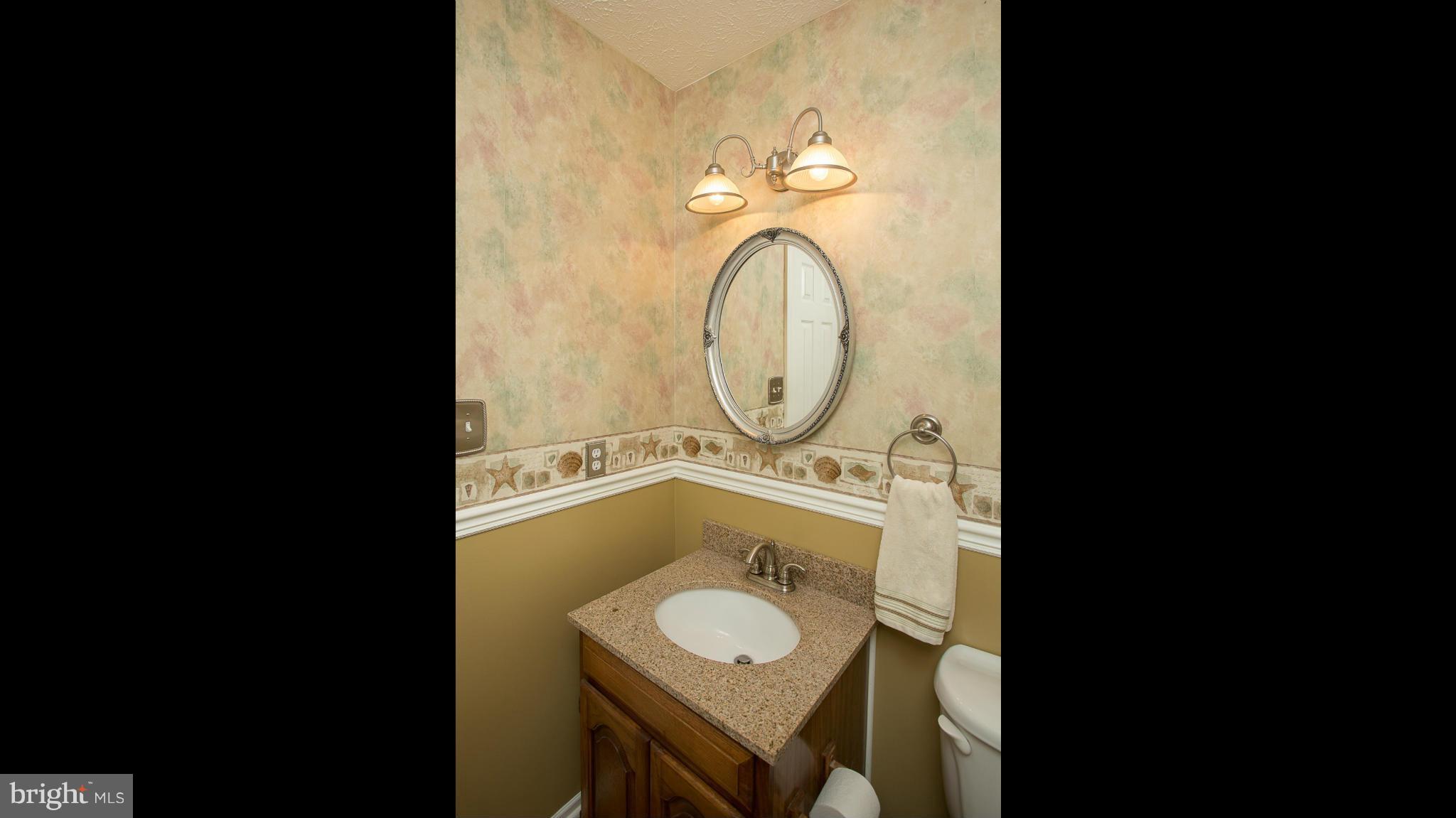 8208 Grassland Road Severn, MD 21144 - Photo 10 of 30 a bathroom with a granite countertop toilet sink and mirror